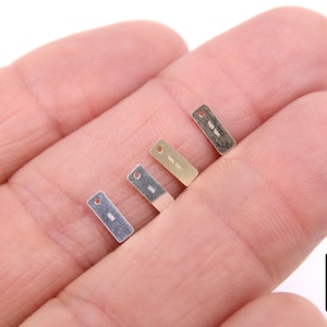 May include: Four small metal tags with a hole at the top. The tags are silver, gold, and two shades of brass. The tags are labeled with the text "10k" and "14k".