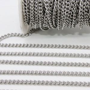 May include: A roll of silver-toned metal chain, with a portion of the chain unrolled to show the detail of the links. The chain is a curb style with a twisted design.