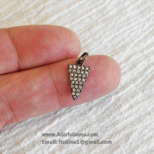 May include: A silver charm in the shape of a triangle, with a black oxidised finish and pave set with clear round diamonds.