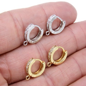 Puede incluir: Dos pares de cierres de aro para pendientes con un acento de cristal transparente. Un par es plateado y el otro es dorado.