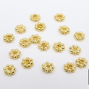 Pu&ograve; includere: Una collezione di 18 distanziatori per perline in metallo dorato con un design a forma di fiore. Ogni distanziatore ha un piccolo foro al centro.