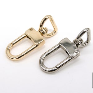 May include: Two metal swivel clasps, one gold and one silver, for attaching straps or chains to bags or other accessories.