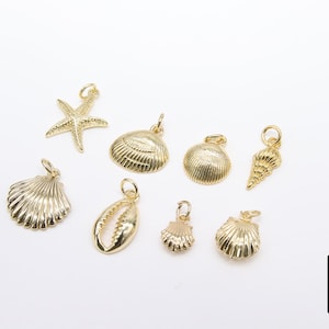 May include: A set of gold-toned metal charms featuring seashells and a starfish. The charms are ideal for jewellery making or adding a touch of nautical style to crafts.