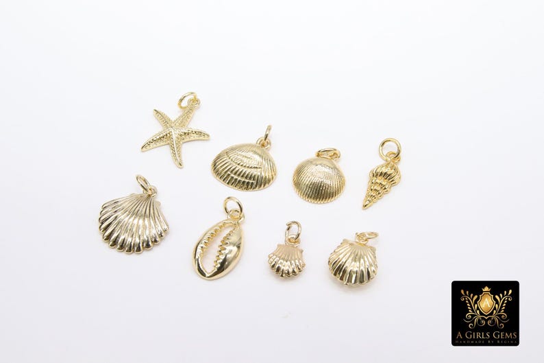 May include: A set of gold-toned metal charms featuring seashells and a starfish. The charms are ideal for jewellery making or adding a touch of nautical style to crafts.