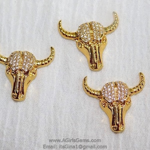 May include: Three gold-tone bull head charms with clear rhinestones. The charms are approximately 1 inch in size.
