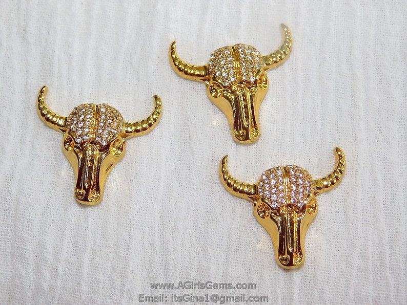 May include: Three gold-tone bull head charms with clear rhinestones. The charms are approximately 1 inch in size.