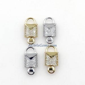 May include: Four lock-shaped charms with a clear crystal-like finish. Two charms are gold, one is silver, and one is a mix of gold and silver. Each charm has a small loop at the bottom.