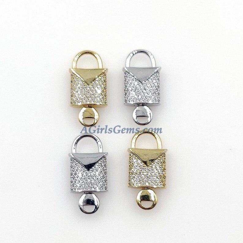 May include: Four lock-shaped charms with a clear crystal-like finish. Two charms are gold, one is silver, and one is a mix of gold and silver. Each charm has a small loop at the bottom.