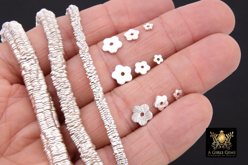 May include: Silver chain necklace with a textured, woven design. The chain is shown with a variety of silver flower-shaped beads in different sizes.