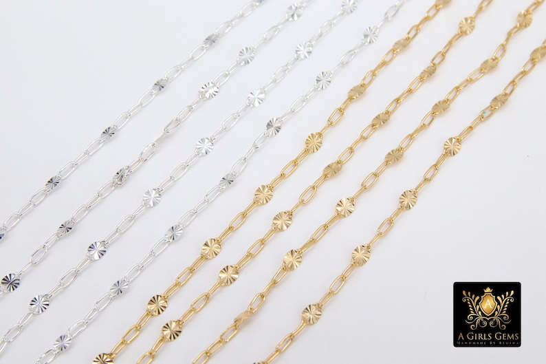 May include: Five strands of chain, two gold and three silver, with a textured, flower-shaped design on each link. The chains are laid out on a white surface.