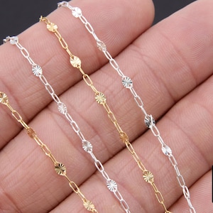 May include: Four strands of chain, each with a different finish: gold, silver, and two shades of silver. The chains are made of small, linked oval shapes with a textured, starburst design.