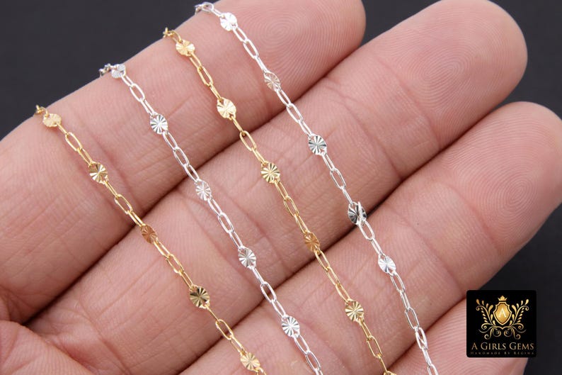 May include: Four strands of chain, each with a different finish: gold, silver, and two shades of silver. The chains are made of small, linked oval shapes with a textured, starburst design.