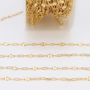 May include: Gold chain with a delicate, patterned design. The chain is made of small, oval-shaped links with a textured surface. The chain is shown in a close-up view, with several strands of the chain laid out in a straight line.
