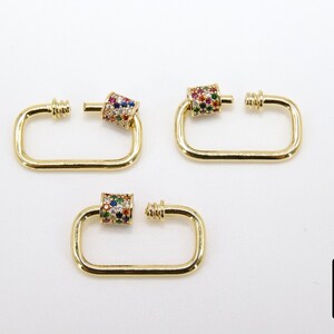 May include: Three gold-toned metal clasps with a colorful, multi-faceted stone design. Each clasp has a rectangular shape with a rounded edge and a small, round, decorative piece on one side.