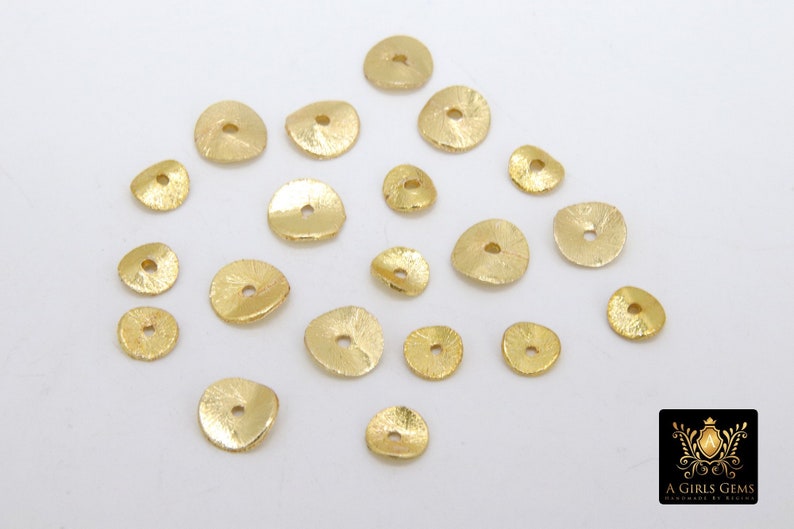 May include: A collection of 20 gold-toned metal beads with a textured surface. The beads are round with a hole in the center.