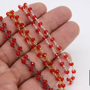 May include: Three strands of red crystal bead chains with different colored metal chain links. The chains are silver, gold, and black.
