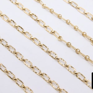 May include: Five gold chains of different lengths, all featuring a textured, oval-link design. The chains are arranged in a staggered pattern on a white background.