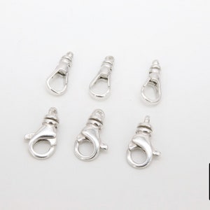 May include: Six silver-toned lobster clasps, each with a spring-loaded opening and a loop for attaching to a chain or cord.