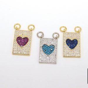 Puede incluir: Tres colgantes de corazón de tono dorado. Cada colgante presenta un corazón de color diferente: rosa, azul y turquesa. Los colgantes están rodeados de piedras de circonita cúbica transparentes.