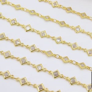 K&ouml;nnte beinhalten: Goldkette mit quadratischen, klaren Steinen. Die Kette besteht aus kleinen, miteinander verbundenen Metallteilen mit einem Stein in jedem Glied.