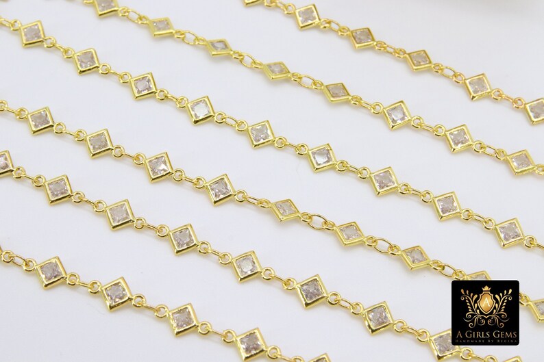K&ouml;nnte beinhalten: Goldkette mit quadratischen, klaren Steinen. Die Kette besteht aus kleinen, miteinander verbundenen Metallteilen mit einem Stein in jedem Glied.