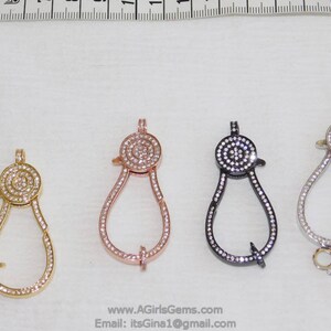 May include: Four different colored metal clasps with a round, clear crystal design. The clasps are in gold, rose gold, silver, and black.