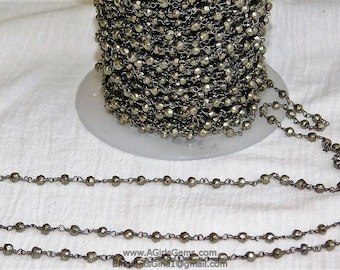 May include: A spool of gold-toned pyrite chain, with a close-up of the chain showing the individual faceted beads and wire links. The chain is laid out on a white surface.