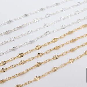 May include: Five strands of silver and gold chain with a decorative, patterned design. The chains are arranged in a fan shape, with the gold chains at the bottom.