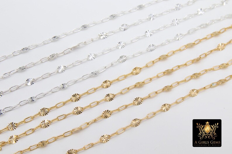 May include: Five strands of silver and gold chain with a decorative, patterned design. The chains are arranged in a fan shape, with the gold chains at the bottom.