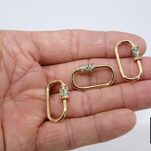 May include: Three gold-toned metal oval-shaped clasps with a colorful crystal-encrusted barrel. Each clasp has a spring-loaded gate.