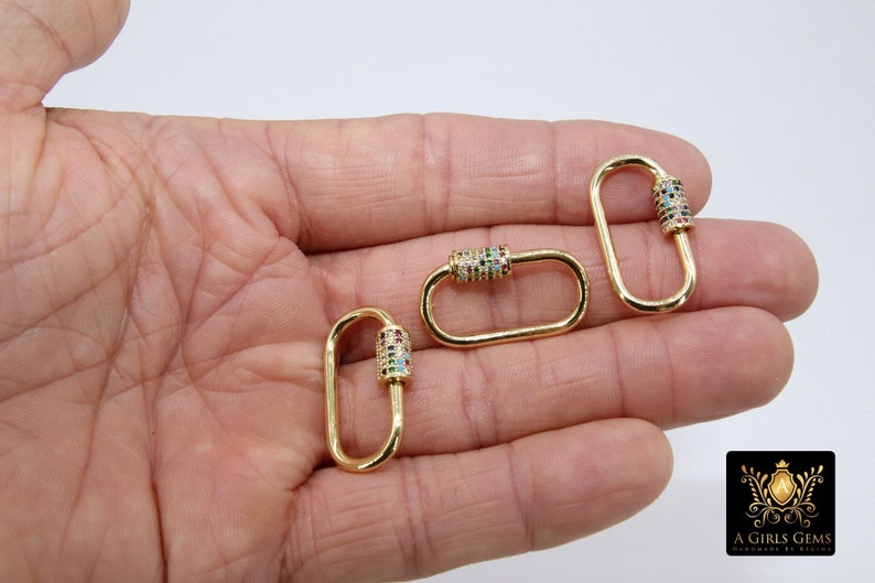 May include: Three gold-toned metal oval-shaped clasps with a colorful crystal-encrusted barrel. Each clasp has a spring-loaded gate.