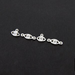 May include: Four silver eye charms with clear rhinestones. Each charm has a loop for attaching to jewelry.