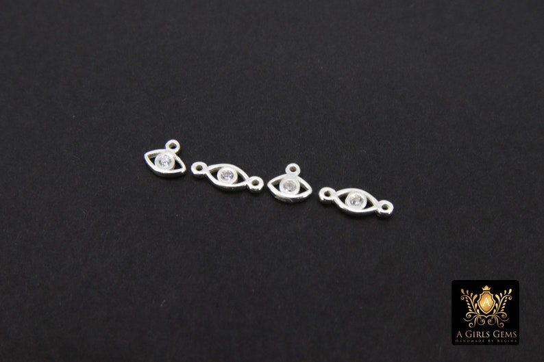 May include: Four silver eye charms with clear rhinestones. Each charm has a loop for attaching to jewelry.