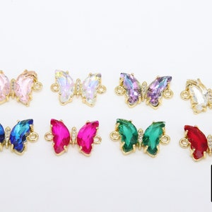 May include: Eight gold butterfly charms with crystal accents in various colors, including pink, white, purple, blue, red, and green. The charms have a loop on each side for attaching to jewelry.