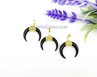 Peut inclure: Trois pendentifs en forme de croissant de lune noirs avec du fil d'or enroulé autour des cornes. Les pendentifs sont sur un fond blanc.