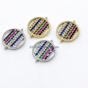 May include: Four round, gold and silver-toned metal charms with a colorful, multi-faceted stone design. The stones are arranged in a striped pattern of blue, green, pink, and black.