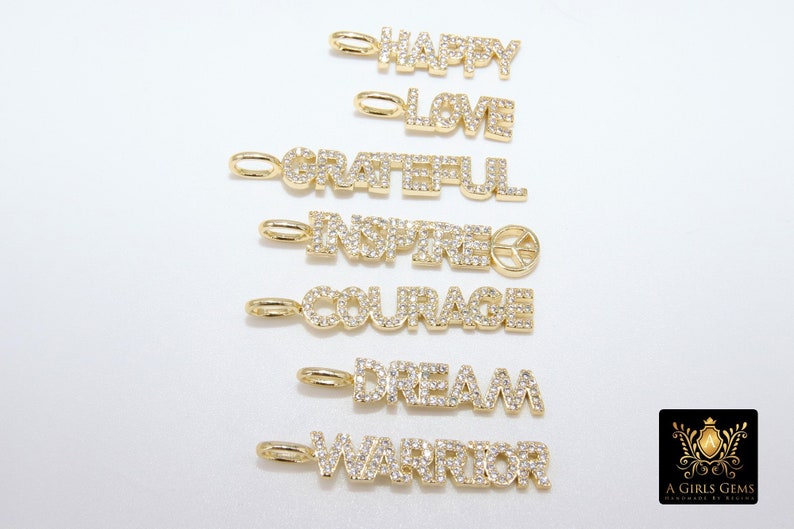 May include: Seven gold charms with diamond-like accents spelling out the words "Happy", "Love", "Grateful", "Inspired", "Courage", "Dream", and "Warrior".