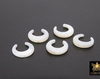 May include: Five white, crescent-shaped, shell beads with a hole in the center.