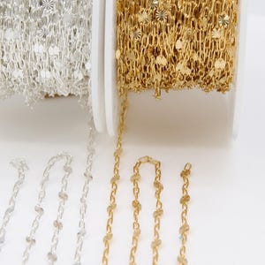 May include: Two spools of chain, one gold and one silver, with decorative round accents. The chain is displayed on a white surface with the brand name "A Girls Gems" in the bottom right corner.