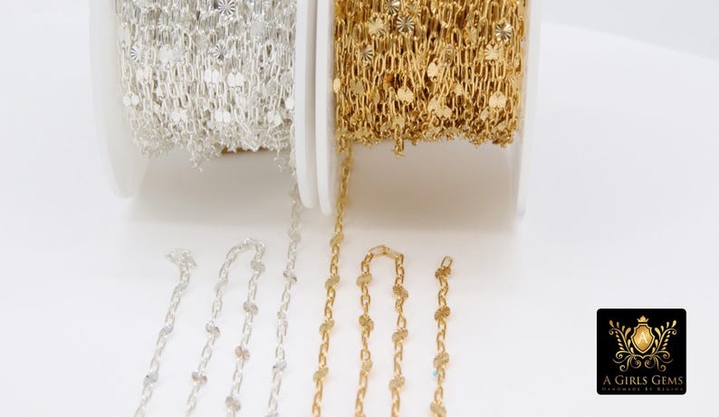 May include: Two spools of chain, one gold and one silver, with decorative round accents. The chain is displayed on a white surface with the brand name "A Girls Gems" in the bottom right corner.