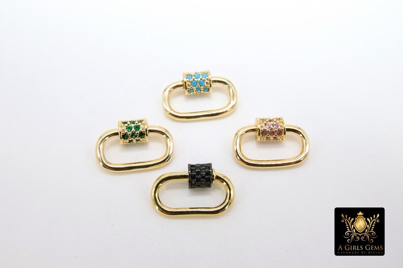 May include: Four gold-colored oval carabiner clasps with different colored gem accents. One clasp has turquoise gems, one has green gems, one has pink gems, and one has black gems. The clasps are on a white background.