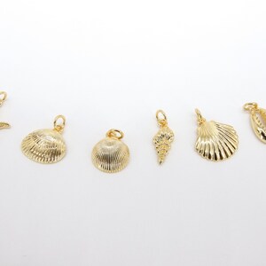 May include: A set of seven gold-coloured charms featuring a starfish and various seashells. The charms are perfect for adding a touch of nautical style to jewellery or crafts.