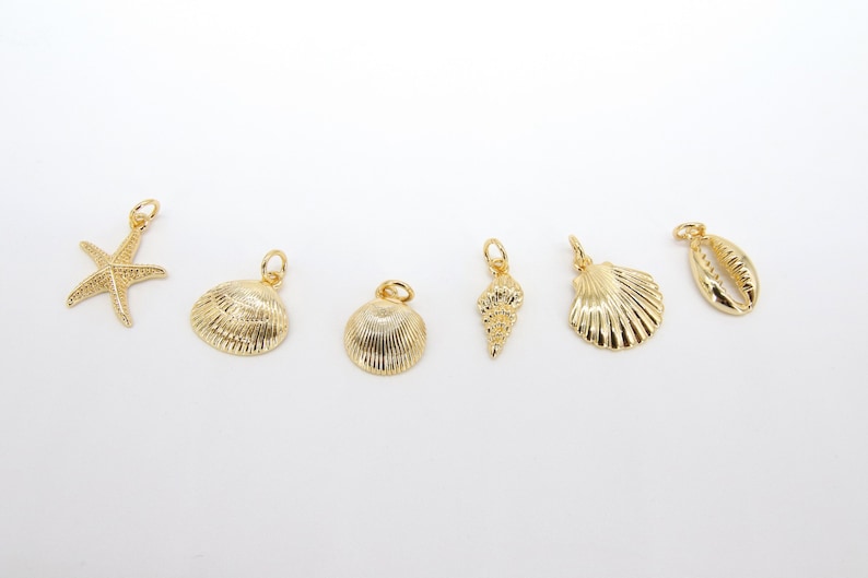 May include: A set of seven gold-coloured charms featuring a starfish and various seashells. The charms are perfect for adding a touch of nautical style to jewellery or crafts.