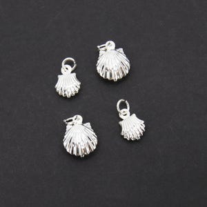 May include: Four silver shell charms with a loop for attaching to a necklace or bracelet.
