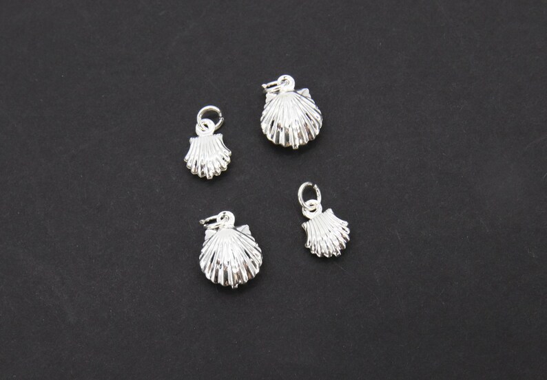 May include: Four silver shell charms with a loop for attaching to a necklace or bracelet.