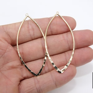 May include: Two gold-toned metal earring hoops with a hammered finish and a teardrop shape.