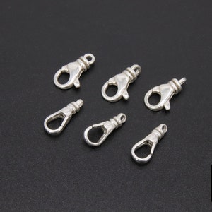 May include: Six silver-toned lobster clasps, a type of fastener used in jewelry making.