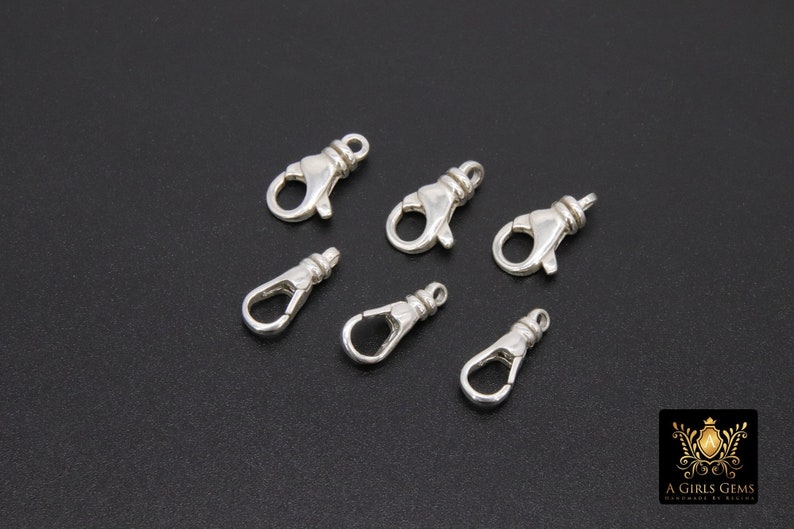 May include: Six silver-toned lobster clasps, a type of fastener used in jewelry making.
