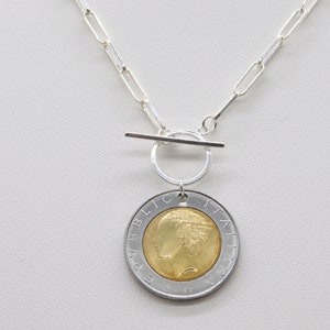 May include: Silver chain necklace with a toggle clasp and a silver and gold coin pendant featuring the text "REPUBLICA ITALIANA".