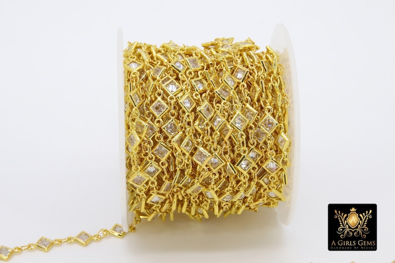 K&ouml;nnte beinhalten: Eine Spule mit goldfarbener Kette mit quadratischen, klaren Kristallen. Die Kette ist aufgerollt und bereit f&uuml;r die Schmuckherstellung.